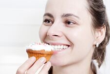 Portrait Of Smiling Girl Eating Muffin Cupcake. Beautiful Young Attractive Caucasian Girl Face Biting Muffin Royalty Free Stock Images