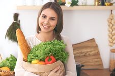 Young Happy Woman Holding Paper Bag Full Of Vegetables And Fruits While Smiling. Girl Have Made Shopping And Ready For Stock Photography
