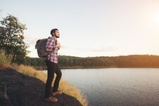 Hipster Hiker Man Standing On The Rock And Enjoying Sunset Over Stock Photography