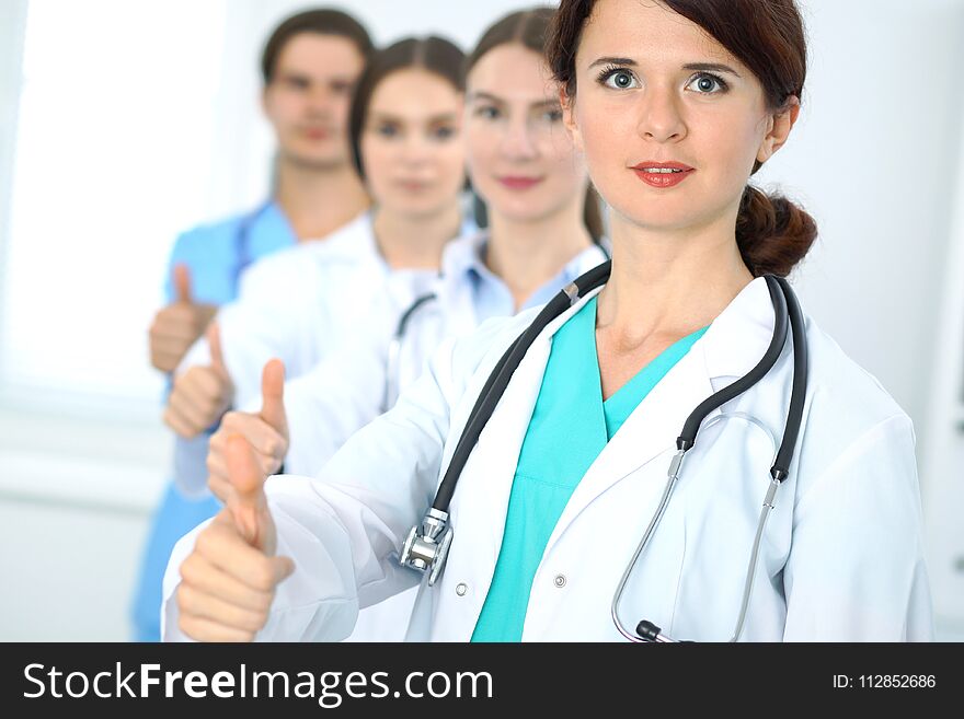 Group of doctors showing OK or approval sign with thumb up. High level and quality medical service, best treatment and