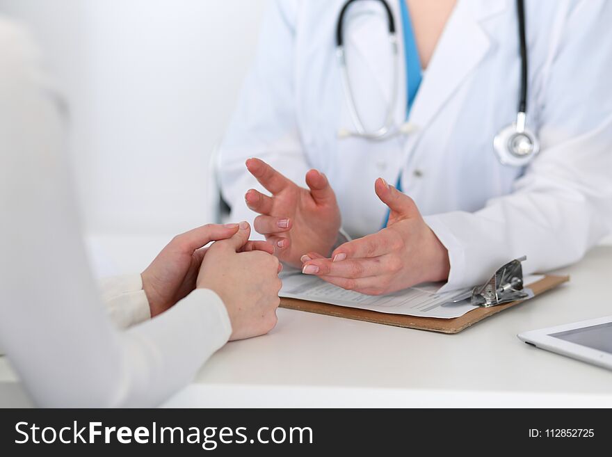 Doctor and patient are discussing something, just hands at the table. Medicine and health care concept