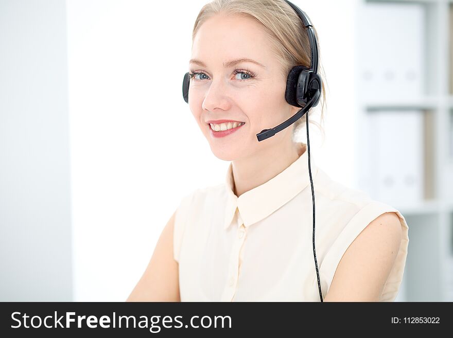 Image of bright call center. Focus on young blonde woman in a headset. Image of bright call center. Focus on young blonde woman in a headset.