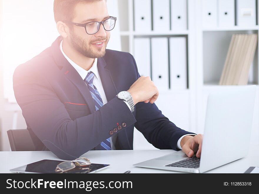 Businessman Using Laptop Computer While Sitting At The Desk In Office. Focus At Cheerful Smiling Bearded Man Wearing