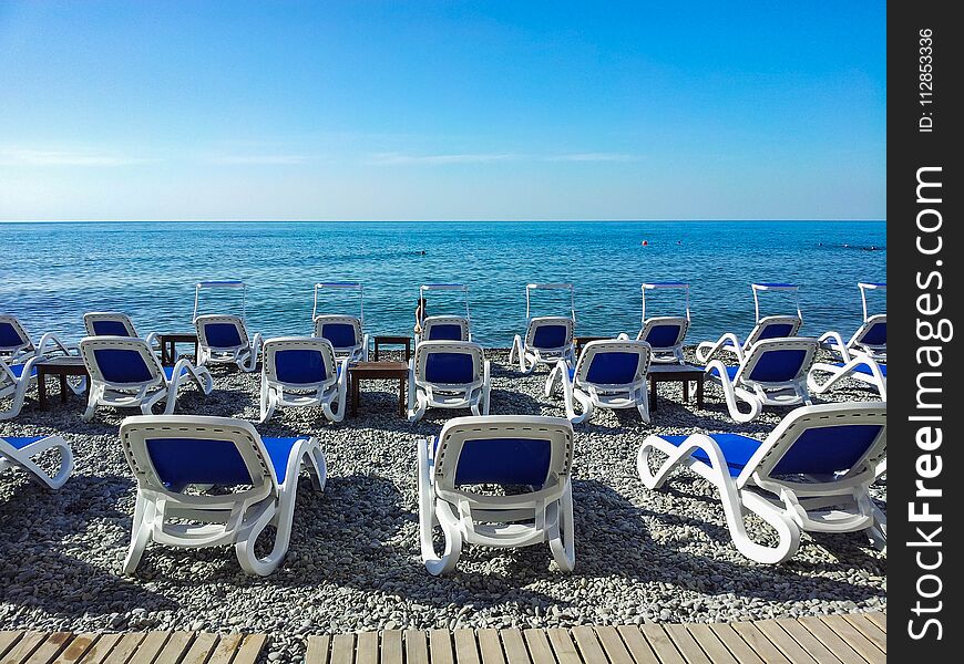 On the beach of small stones there are trestles for rest on the background of the sea. On the beach of small stones there are trestles for rest on the background of the sea