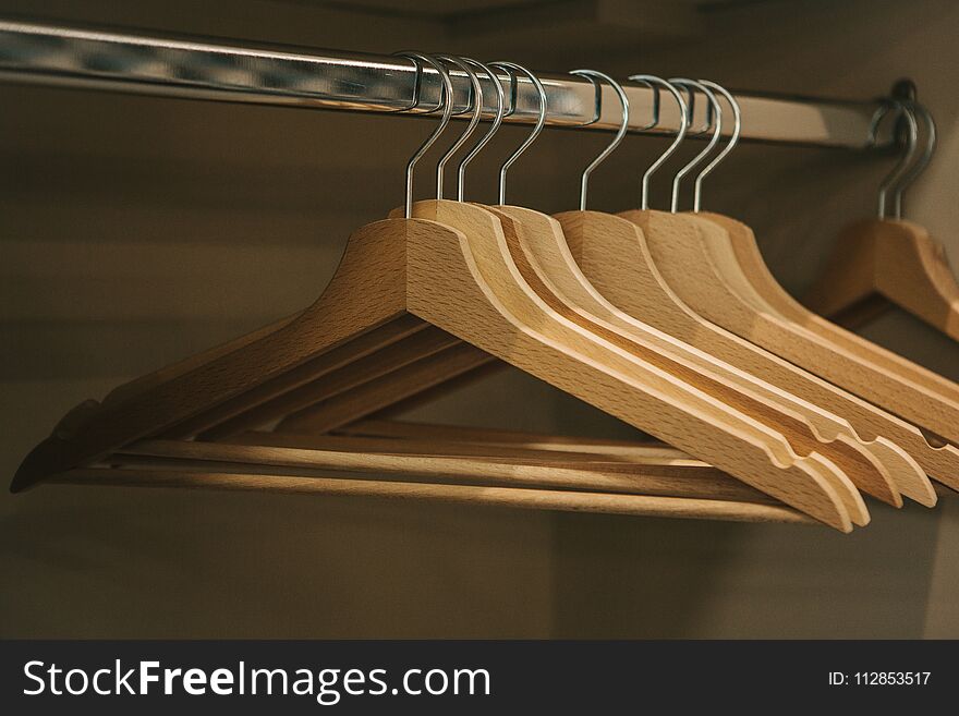 Empty hangers hang in a row in the closet.