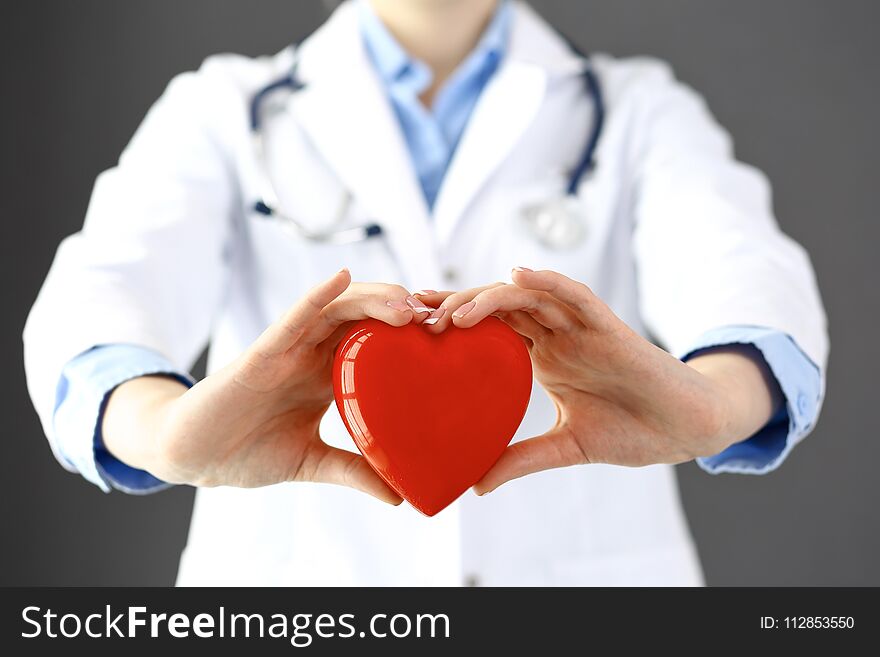 Female doctor with stethoscope holding heart in her arms. Healthcare and cardiology concept in medicine.