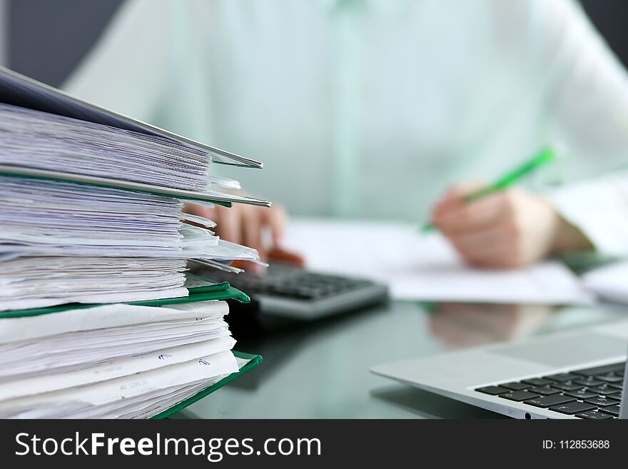 Bookkeeper or financial inspector making report, calculating or checking balance. Binders with papers closeup. Audit and tax service concept. Green colored image background.