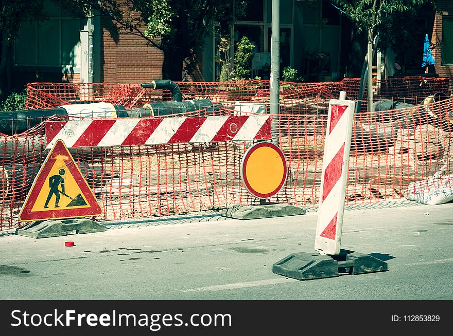 Work ahead street construction and reconstruction site with warning sign dead end and orange fence net as road barricade and barriers for cars and pedestrians caution. Work ahead street construction and reconstruction site with warning sign dead end and orange fence net as road barricade and barriers for cars and pedestrians caution