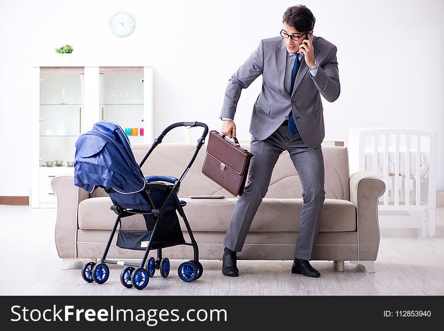 The businessman looking after newborn baby at home and teleworking