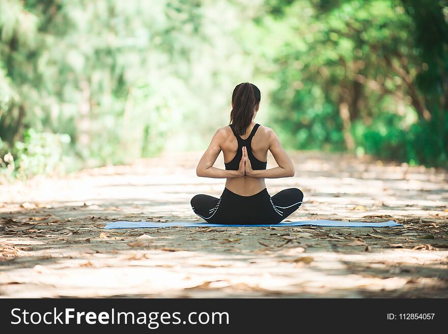 Young asian woman doing yoga in the morning at the park. Healthy lifestyle concept.