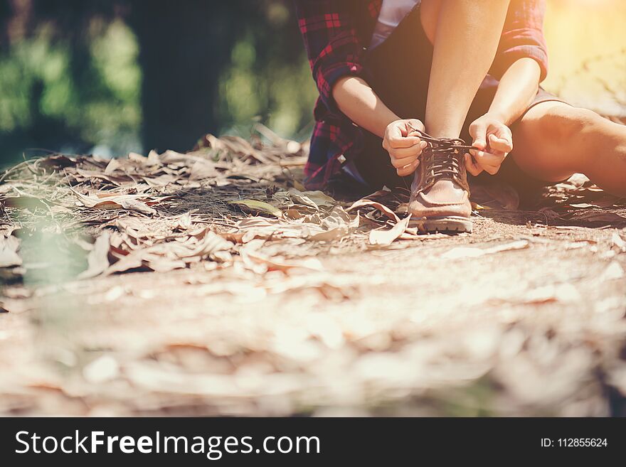 Young woman hiker stops to tie her shoe on a summer hiking trail
