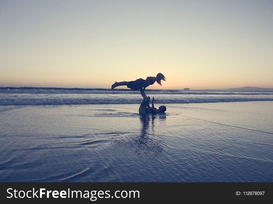 Landscape Photography of Man Lifting Woman by His Foot on Seashore