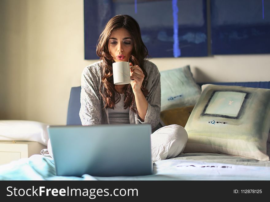 Woman in Grey Jacket Sits on Bed Uses Grey Laptop