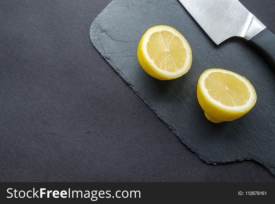 Sliced Lemon Beside Knife on Top of Black Surface