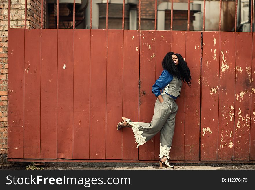 Woman Wearing Grey Jumpsuit Standing Beside Brown Metal Gate