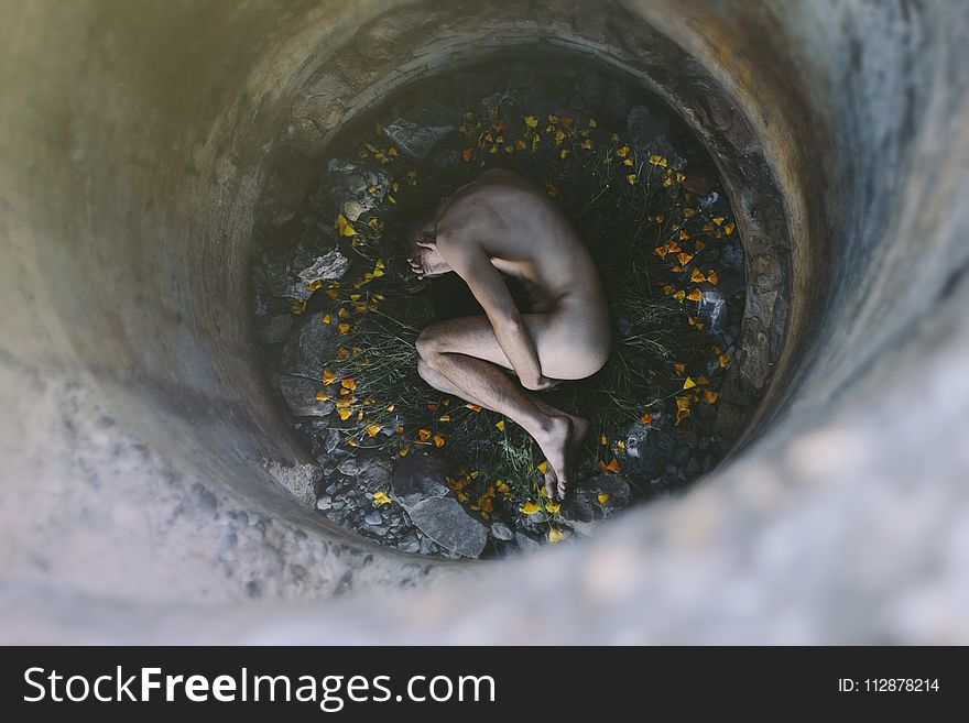 Nude Person Inside Well Laying on Flowers