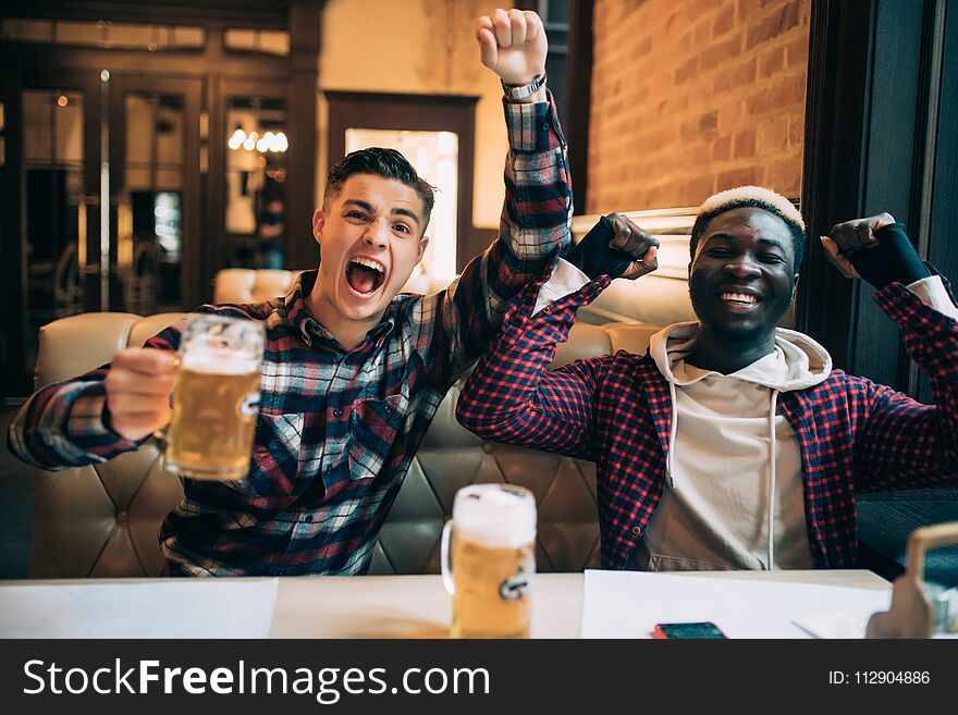 Cheerful Male Friends Having Fun At The Beer Pub Celebrating Victory Of Their Favorite Team Watching Game On TV And Shouting