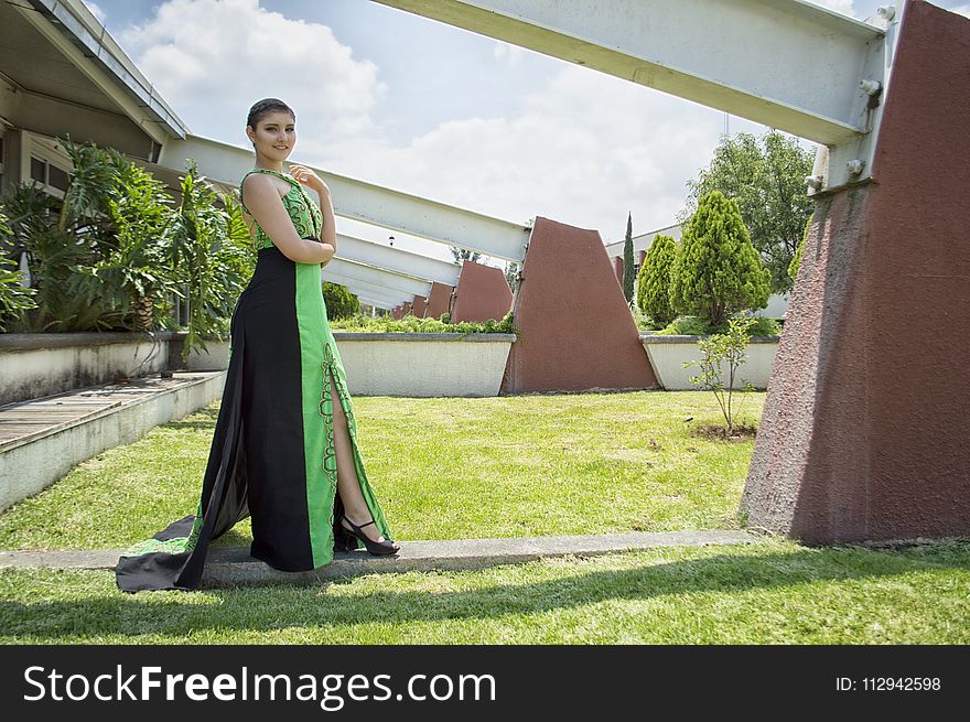 Woman in Green and Black Dress Standing in Front of Wall