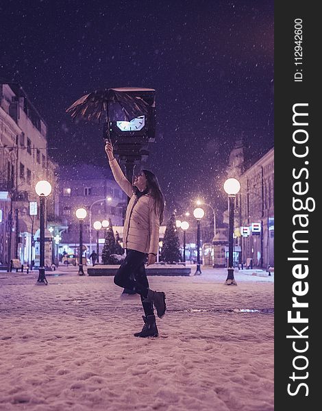 Woman in White Bubble Jacket and Black Jeans Standing While Holding Umbrella