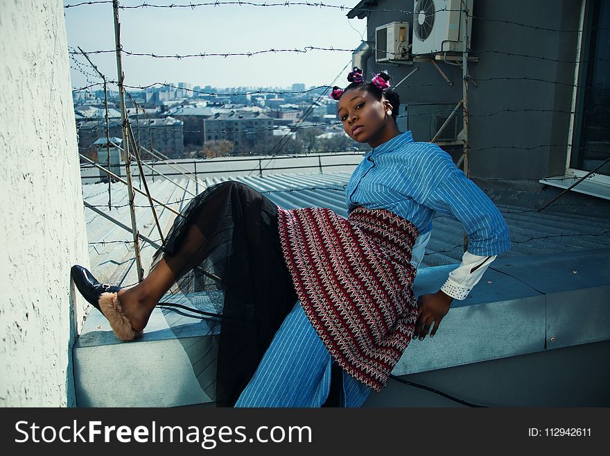 Woman in Blue and Red Dress Posing in Quirky Style on White Wall With Barb Wires