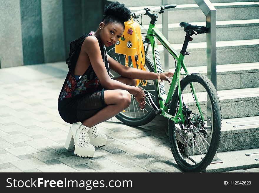 Woman Wearing Black Dress Seating Near Green Bicycle