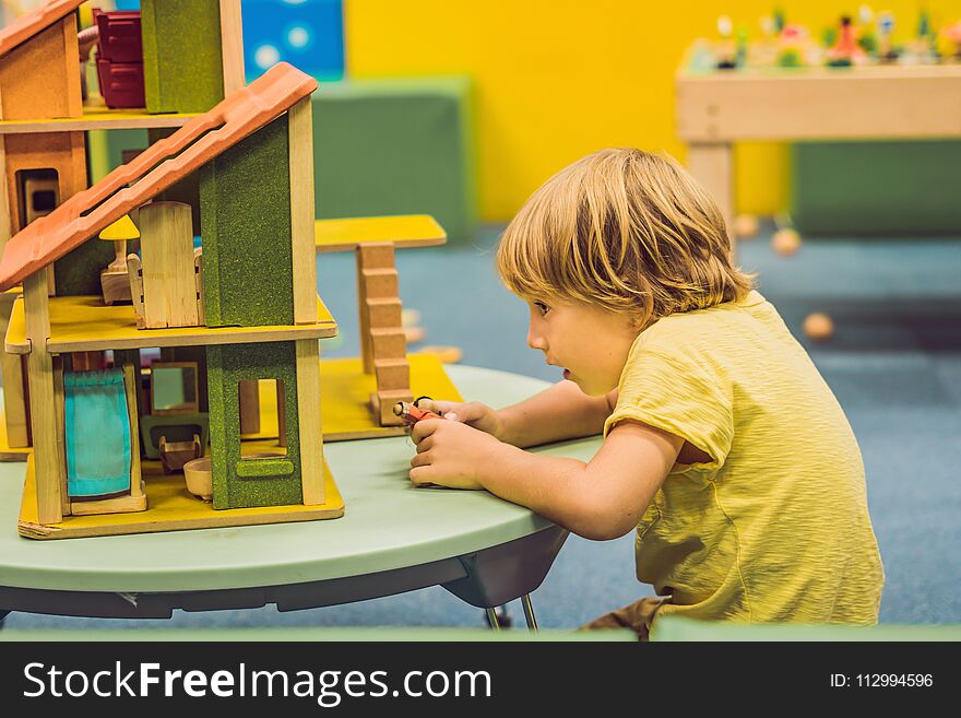 Boy playing with wooden house in kindergarten