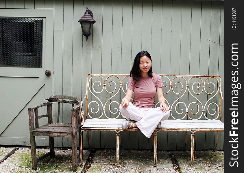 Pretty Korean girl sitting on an antique iron bench. Pretty Korean girl sitting on an antique iron bench