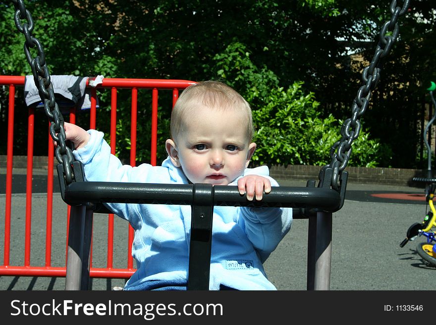 Happy child playing on swing in playground