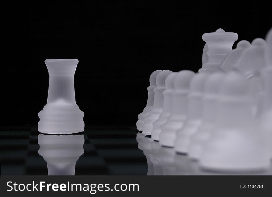 A rook from a glass chess set is out of line with rows of pieces from the same side. A rook from a glass chess set is out of line with rows of pieces from the same side.