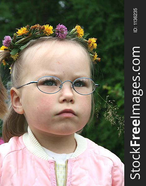 A girl wearing glasses and wreath of flowers outdoor. A girl wearing glasses and wreath of flowers outdoor