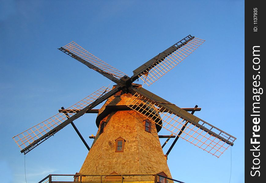 Windmill against blue sky with blades tied down