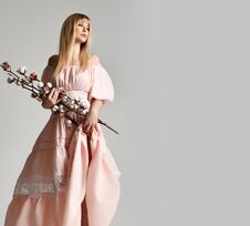 Blonde Woman In Pastel Color Light Pink Dress Walk With Bouquet Of Natural Cotton Flowers On Gray Royalty Free Stock Image