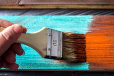 Brush With Paint In Hand. A Man Paints Blue Boards In A Brown Paint Brush. Stock Photo