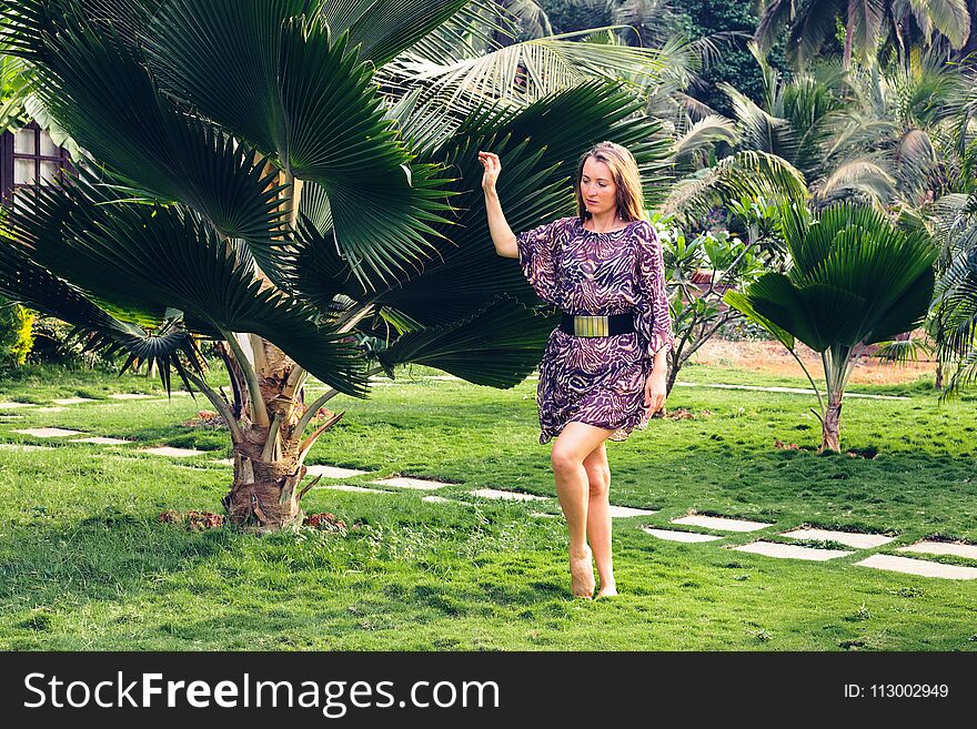 Slender girl with a beautiful tan on a tropical green jungle background. Lifestyle travel and prosperity. Vacation concept the resort in paradise places. Slender girl with a beautiful tan on a tropical green jungle background. Lifestyle travel and prosperity. Vacation concept the resort in paradise places.