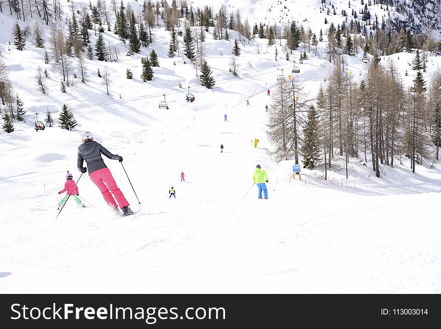 The peaks of the Alps mountains covered with snow. the ski slopes crowded with skiers on a sunny winter day. The peaks of the Alps mountains covered with snow. the ski slopes crowded with skiers on a sunny winter day