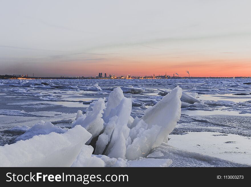 Icey Baltic sea with Tallinn`s skyline behind it during a sunset