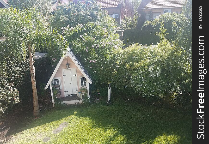 A little house in a beautiful garden on a sunny day with a clear skies surrounded by nature, trees and flowers. A little house in a beautiful garden on a sunny day with a clear skies surrounded by nature, trees and flowers