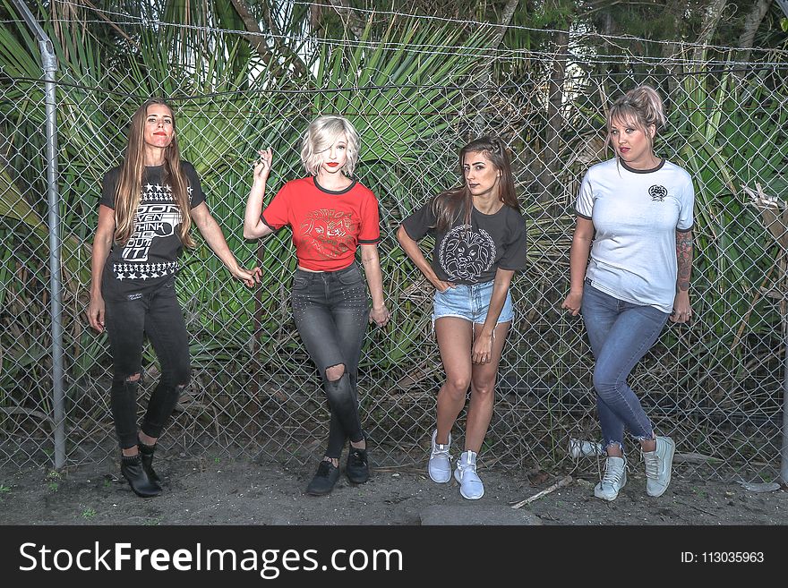 Four Women Standing Near Gray Chain Fence
