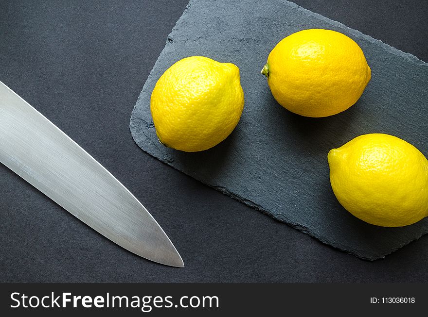 Photo of Three Lemons on Chopping Board Near Knife