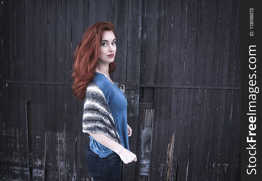 Photo Of A Woman Wearing Blue Shirt Behind Black Wooden Wall