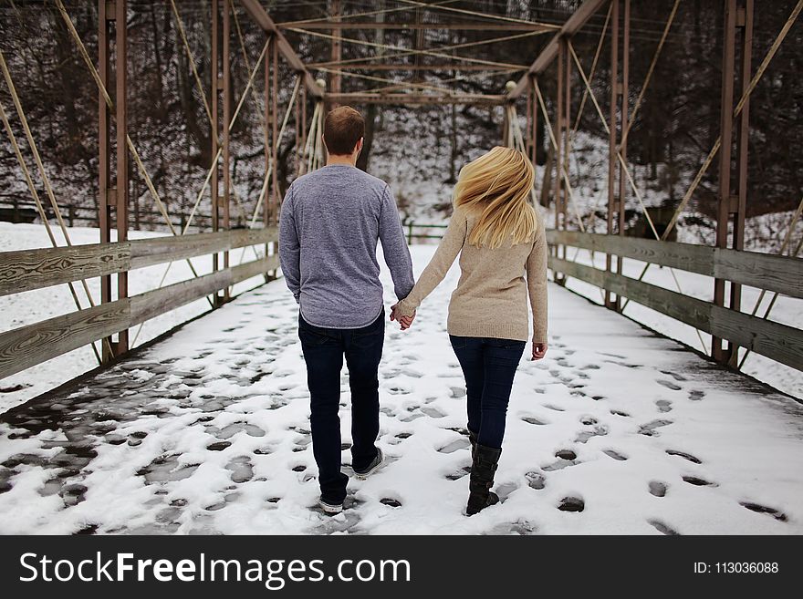 Man and Woman Walking on Snow Covered Road