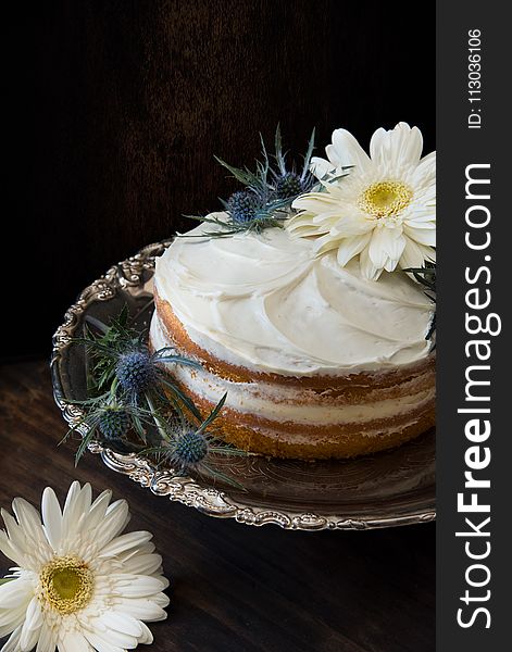 Fondant Cake Whipped With White Icing and Topped With White Petaled Flower on Grey Stainless Steel Plate