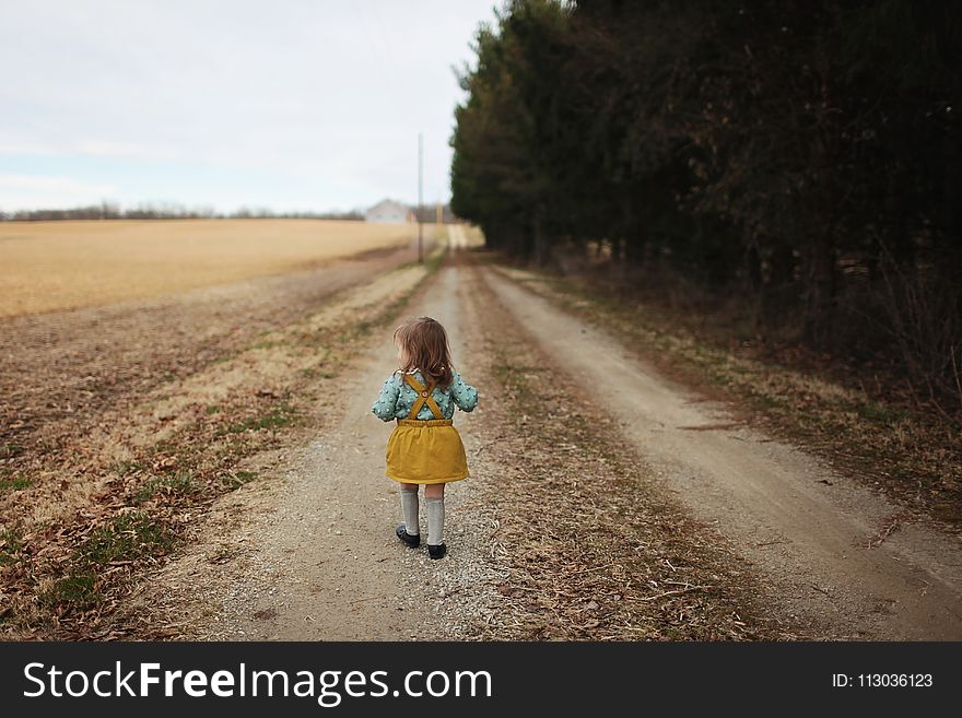 Girl Wearing Blue Long-sleeved Shirt and Yellow Skirt Walking on Pathway
