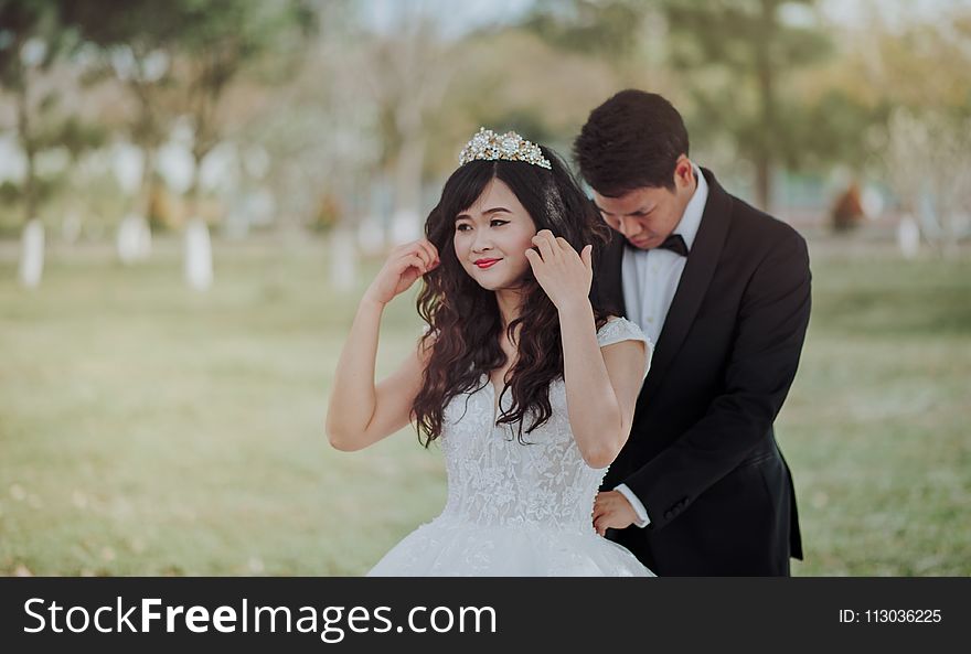 Groom Tying Bride&#x27;s White Lace Wedding Gown at the Back