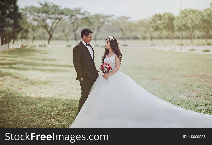 Woman Wearing Wedding Dress Standing Beside a Man Wearing Tuxedo