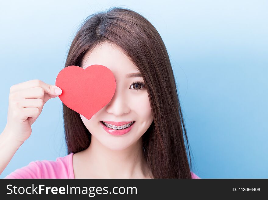 Woman wear brace and take heart on the blue background. Woman wear brace and take heart on the blue background