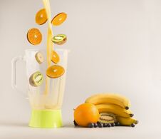 Flying Ingredients For Making Smoothies From Oranges, Kiwi And Bananas, Vegetarian Healthy Food, Fruit Lined Around A Green Blende Royalty Free Stock Photo