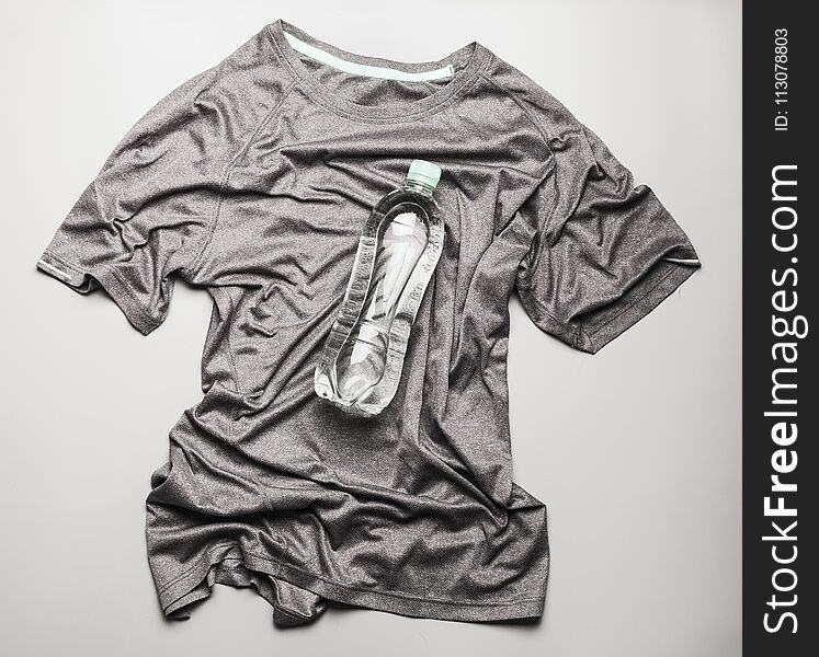 Sports t-shirt for jogging and training in the gym, on which lies a bottle of water with measuring tape, the concept of a sport