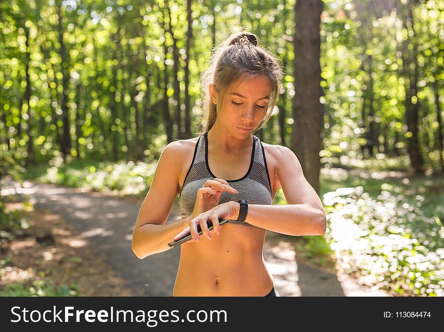Young athlete woman checking fitness progress on her smart watch. Female runner using fitness app to monitor workout