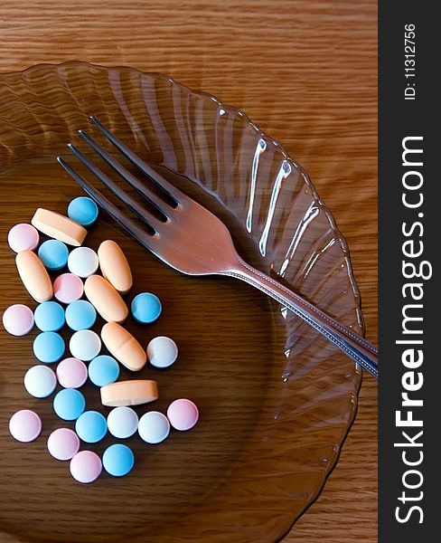 Plate with coloured vitamins and a fork on it. Plate with coloured vitamins and a fork on it